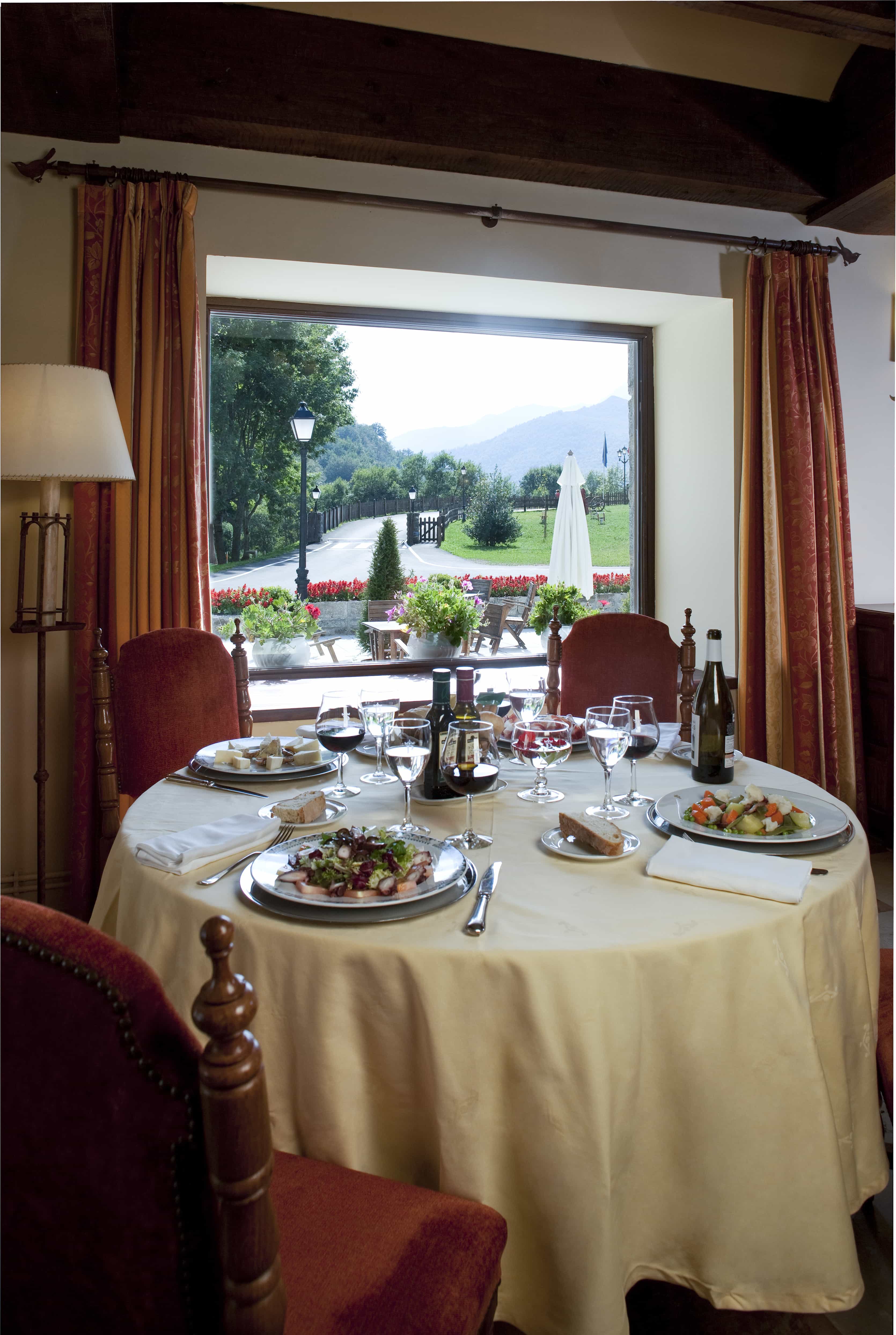 Mesa preparada con platos tradicionales en el comedor del Restaurante del Parador de Fuente Dé con vistas al jardín