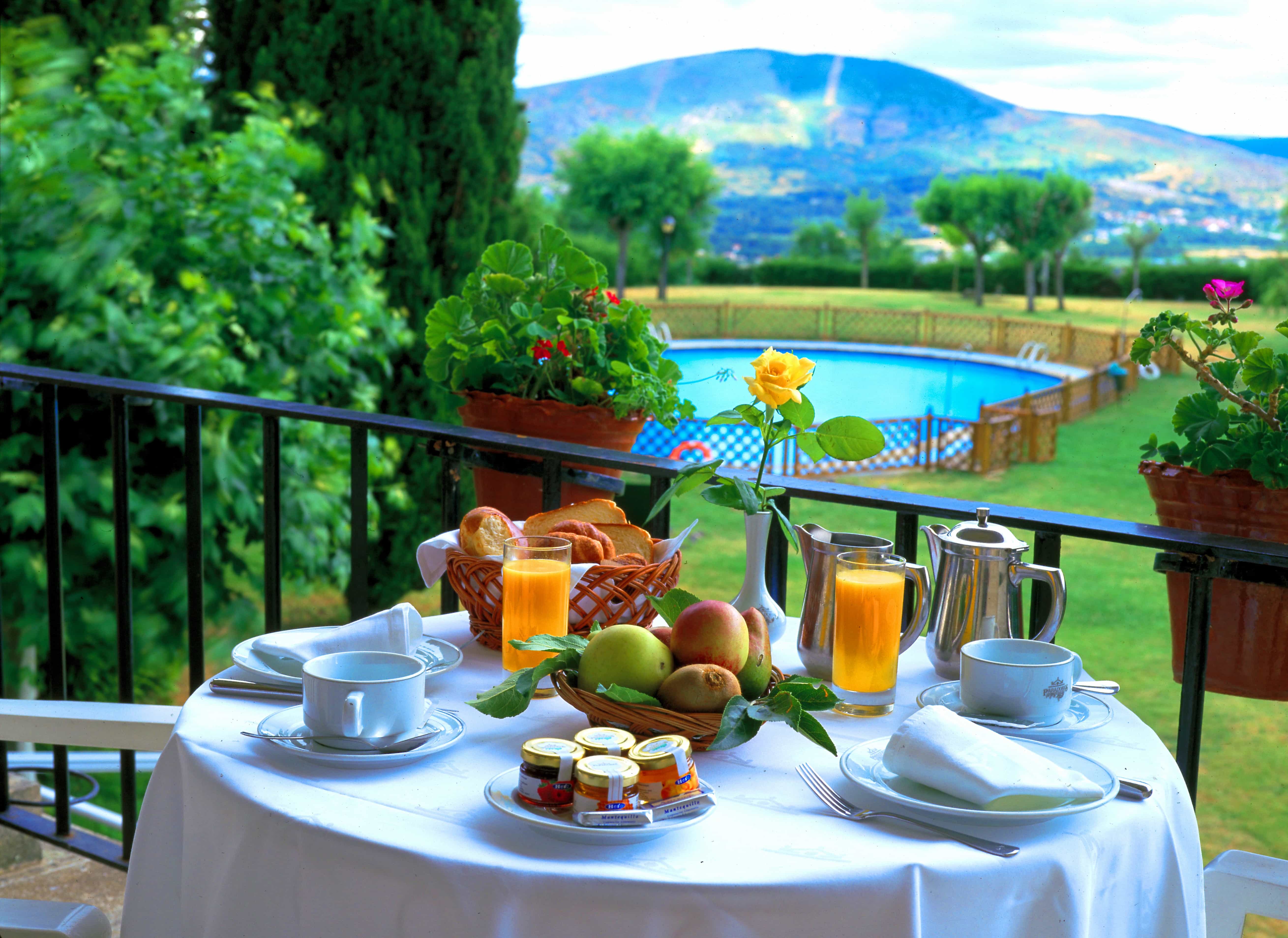 Desayuno preparado en mesa exterior con vista a prados verdes con las montañas de Verín al fondo