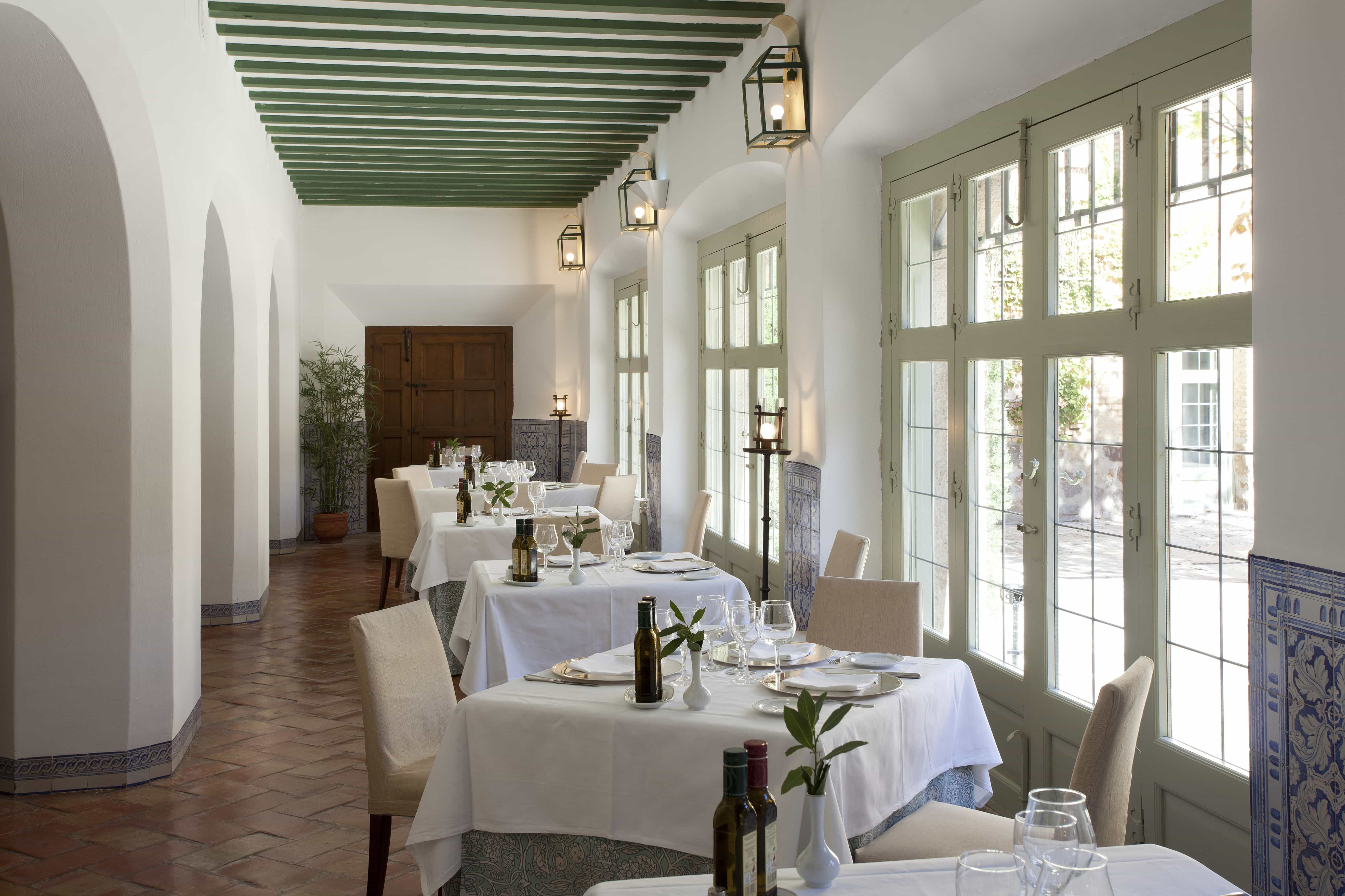 Mesas del comedor del Restaurante del Parador de Almagro iluminadas por luz natural procedente de la galería