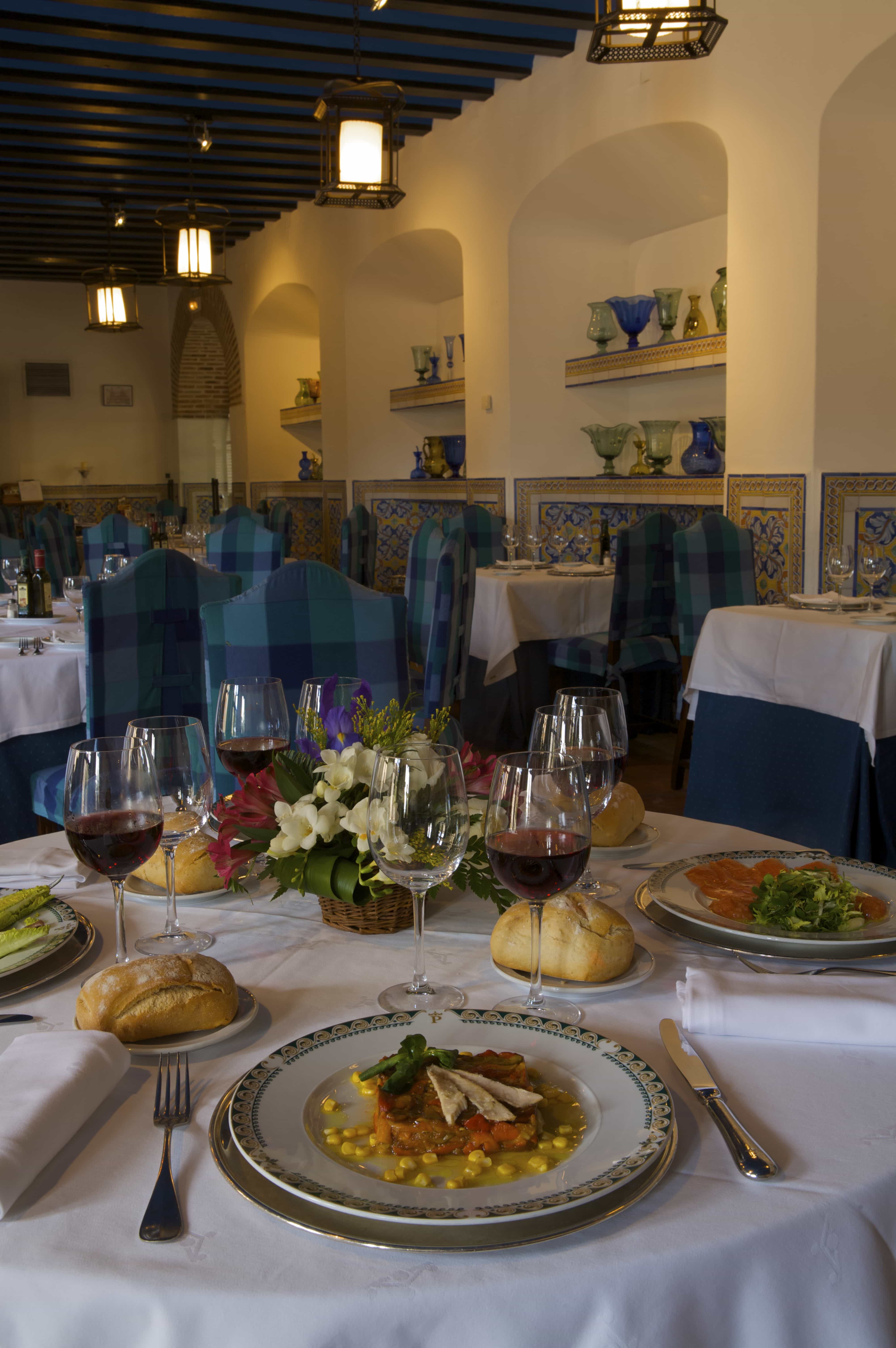 Mesa servida con platos de comida en el comedor del Restaurante El Convento del Parador de Chinchón