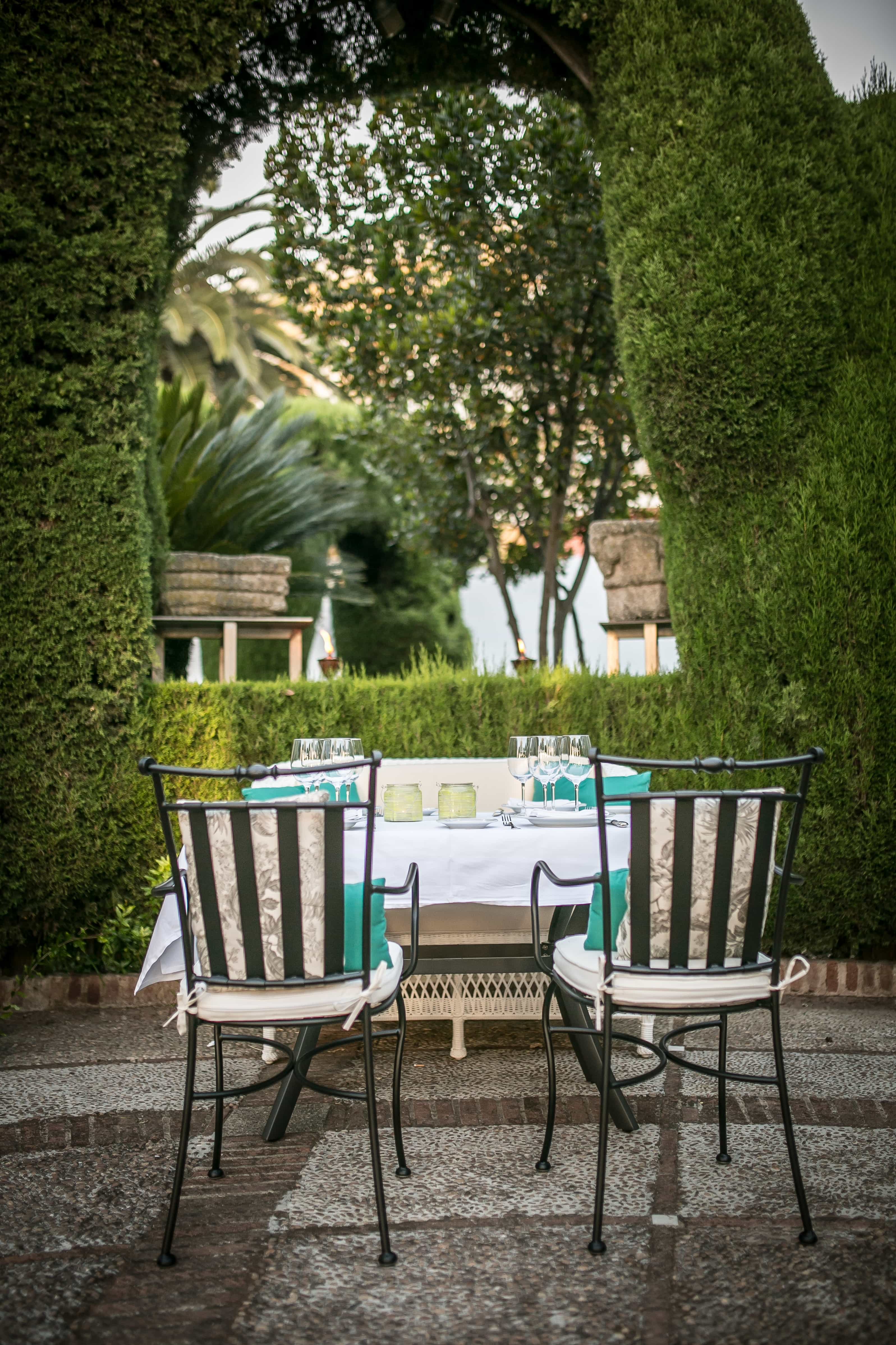 Mesa en la terraza exterior junto a enredaderas verdes en el Restaurante del Parador de Mérida