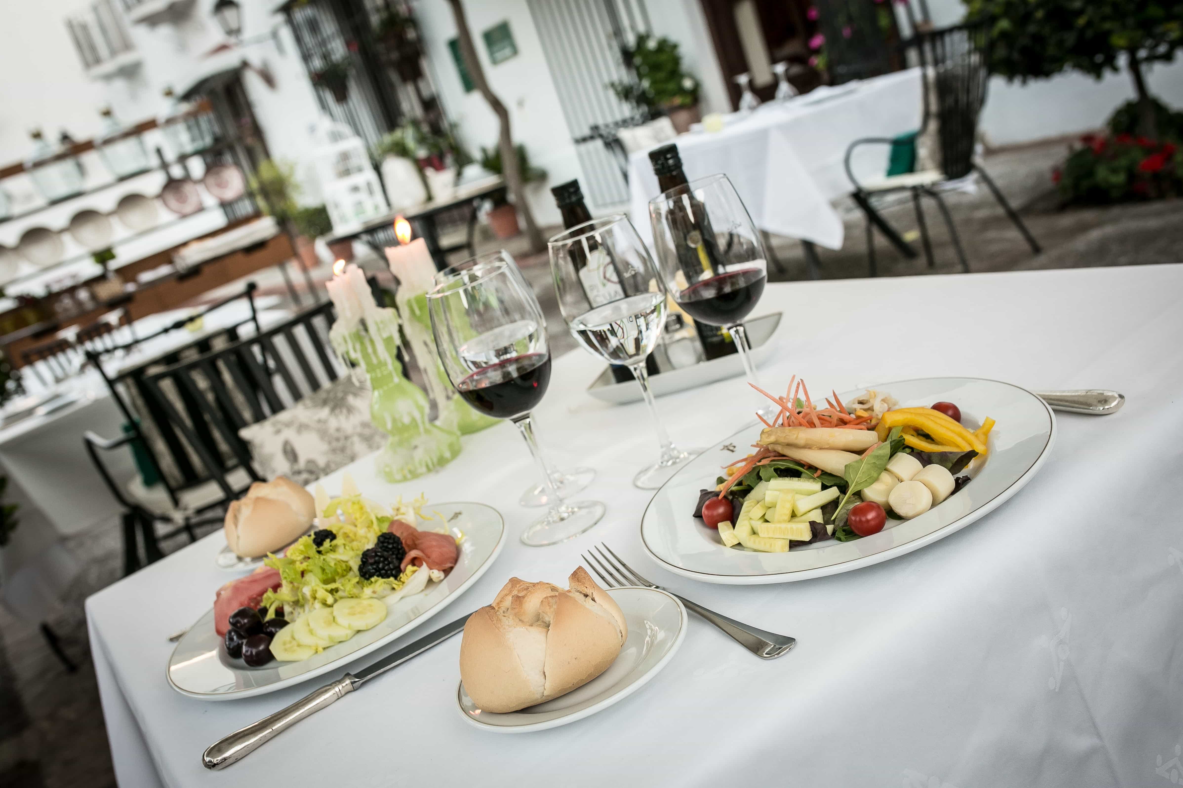 Mesa servida con platos tradicionales y copas de vino en el Restaurante del Parador de Mérida