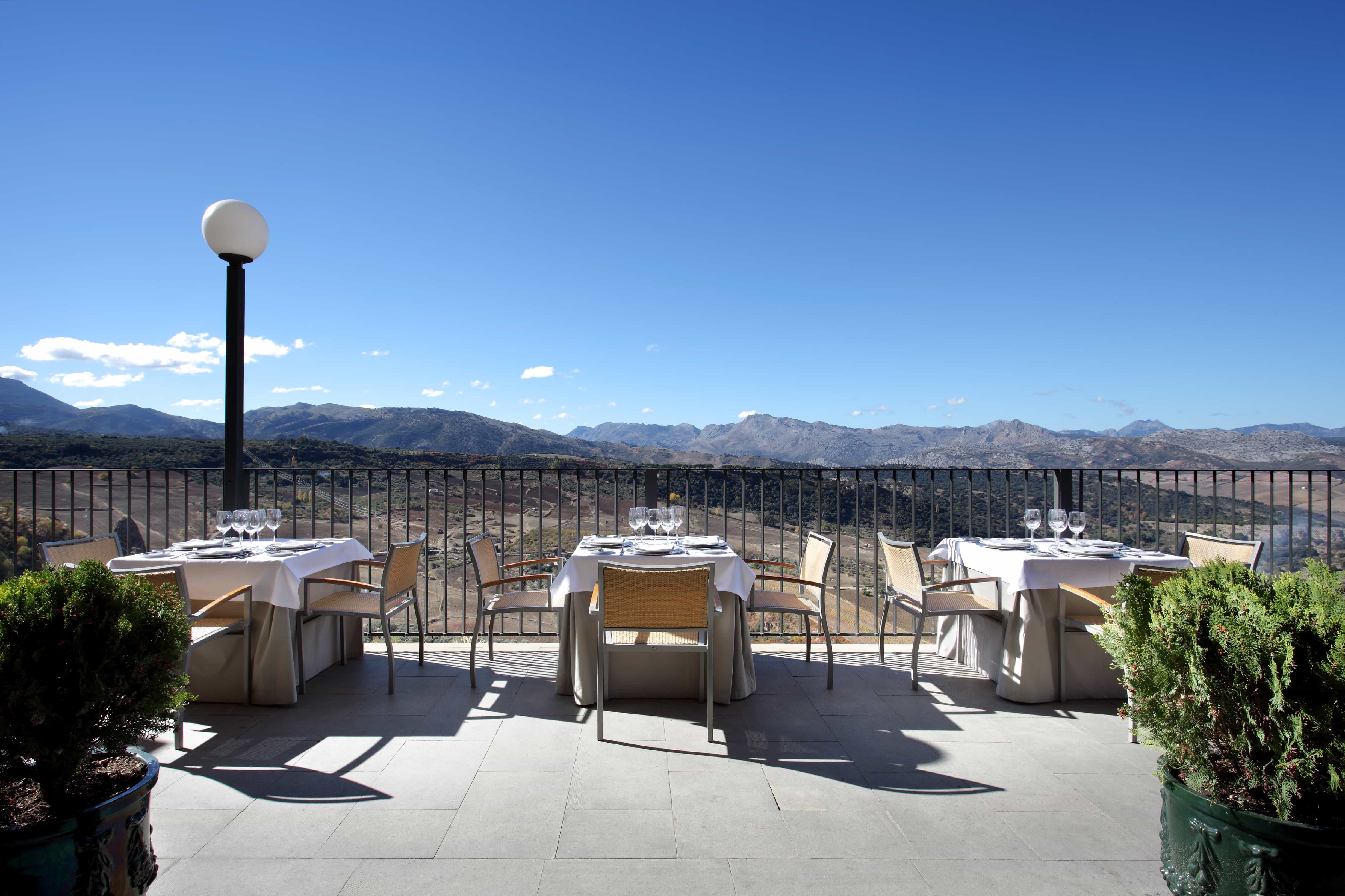 Terraza exterior del Restaurante del Parador de Ronda con el cielo despejado y las montañas al fondo