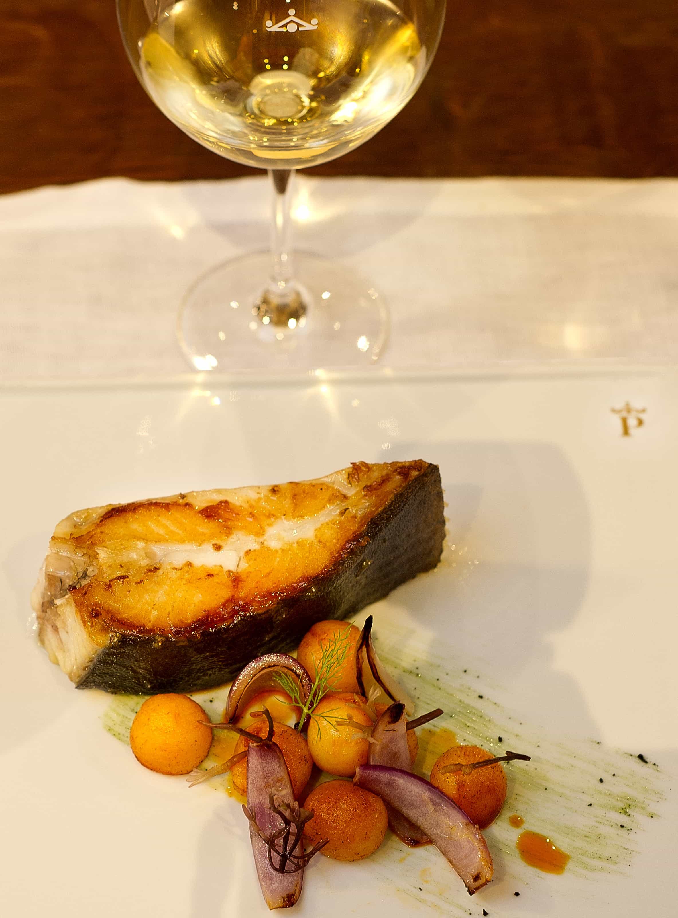 Plato de pescado con copa de vino blanco del Restaurante Enxebre Parador de Santiago de Compostela