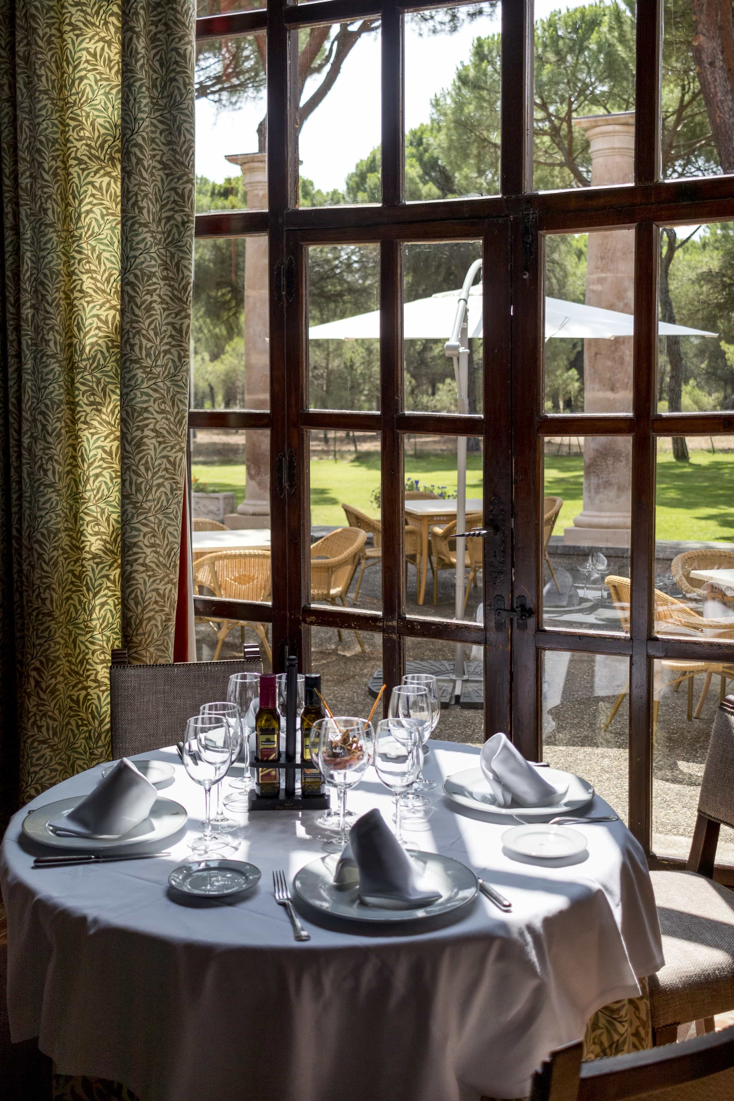 Mesa preparada junto a la ventana del comedor del Restaurante del Parador de Tordesillas con vistas al pinar