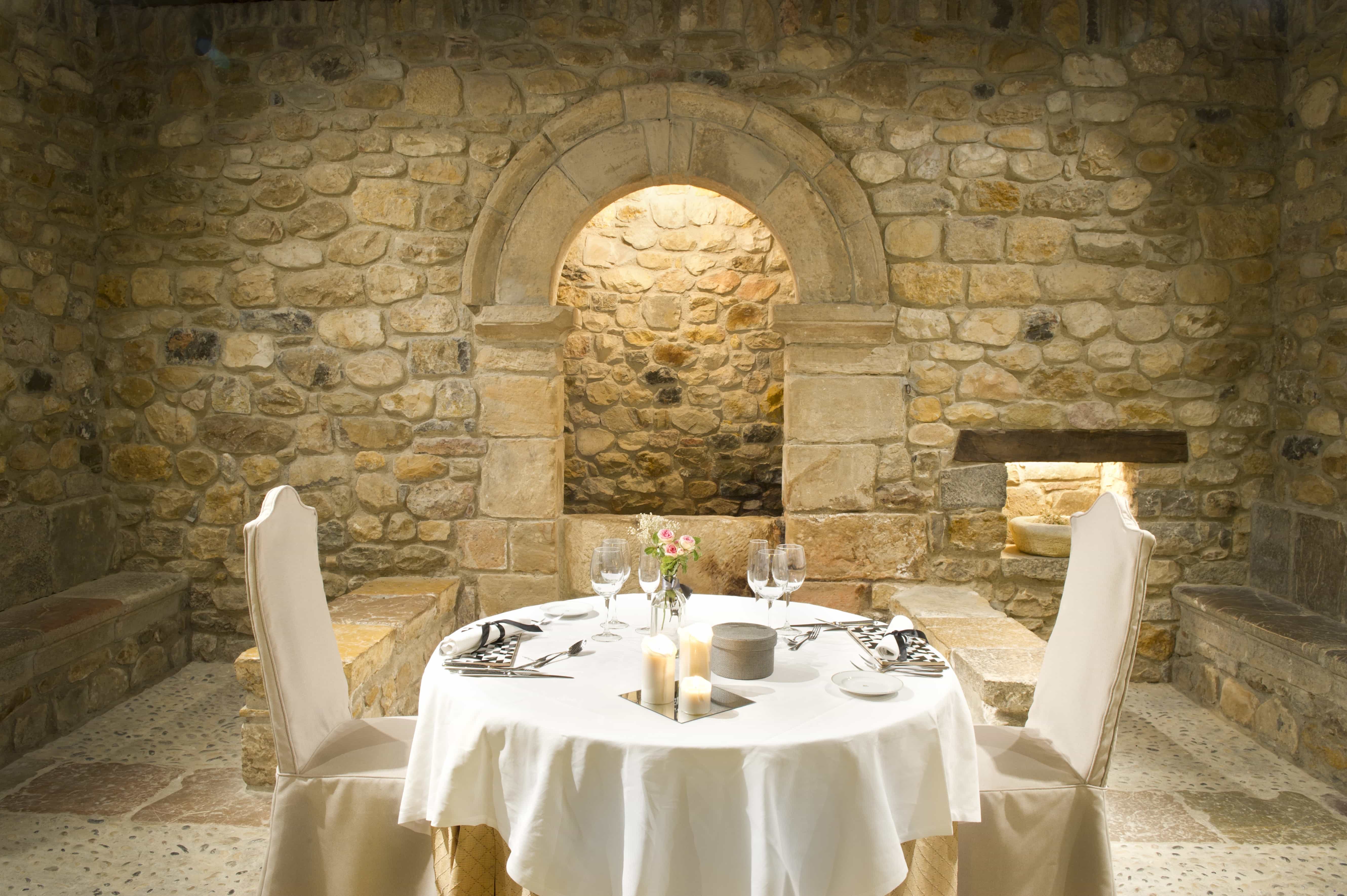 Mesa preparada para dos en el comedor monumental con paredes de piedra del Restaurante del Parador de Cangas de Onís