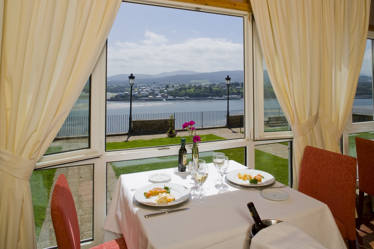 Mesa servida junto a ventana con vistas a la ría del Restaurante del Parador de Ribadeo