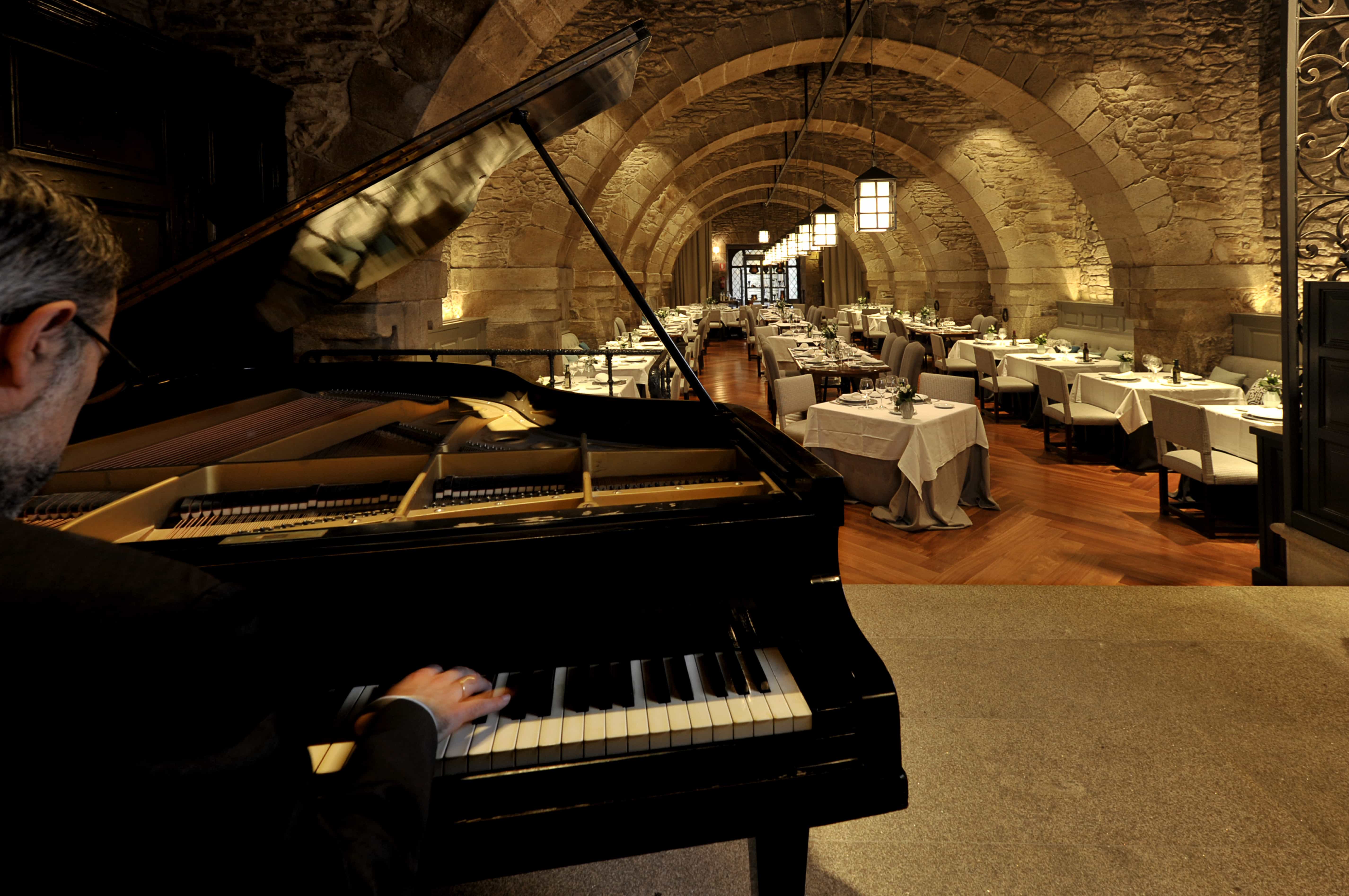 Vista del piano en el comedor con arcos de piedra del Restaurante dos Reis