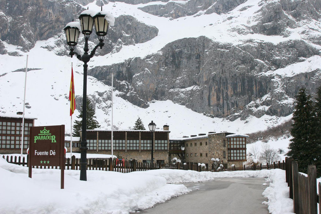 Fachada del Parador de Fuente Dé nevado con la montaña al fondo