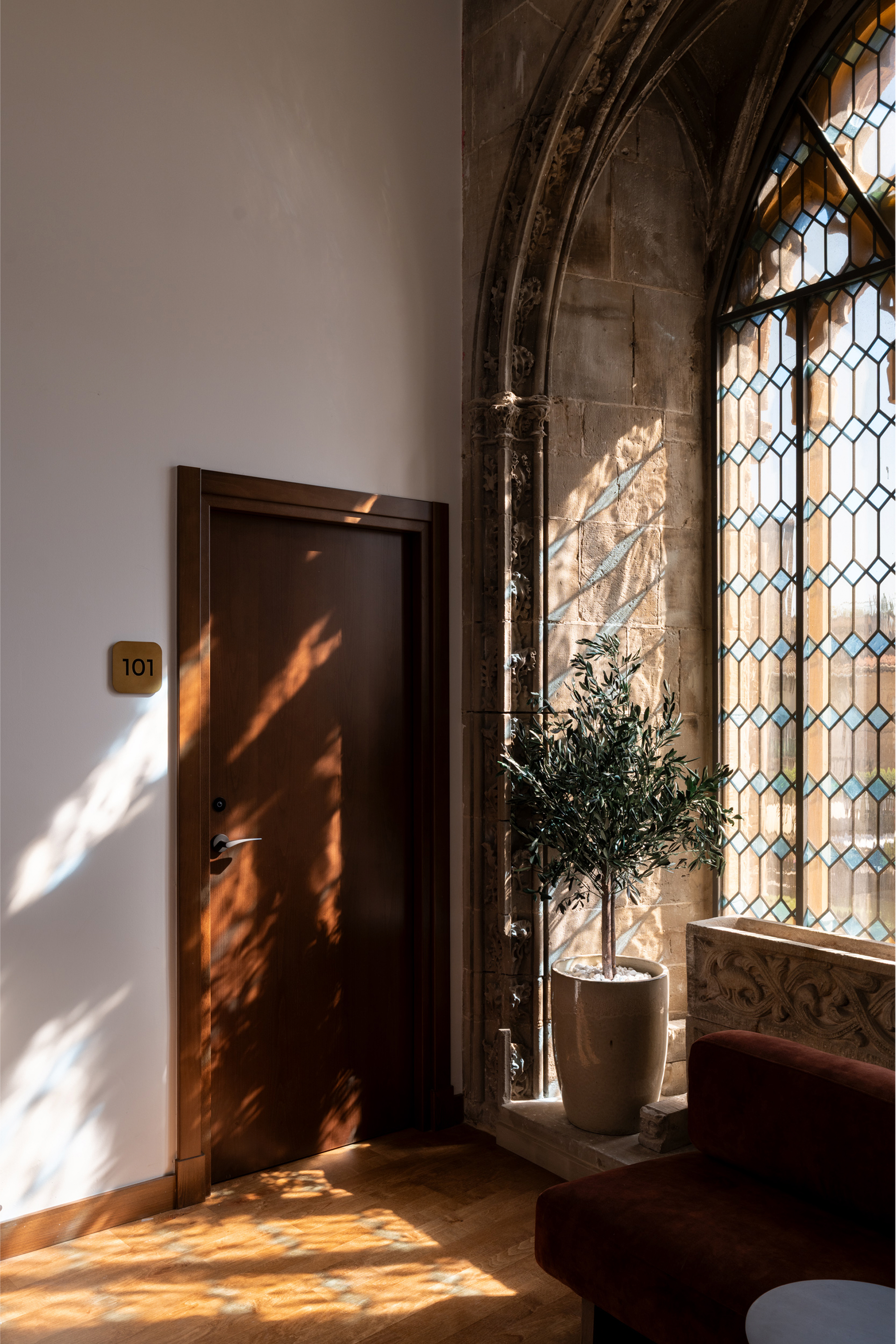Imagen que muestra la puerta de una habitación junto a un ventanal de vidriera coloreada