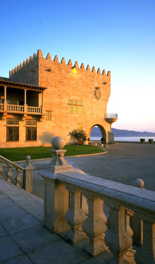 Fachada del Parador de Baiona iluminada al amanecer desde la entrada