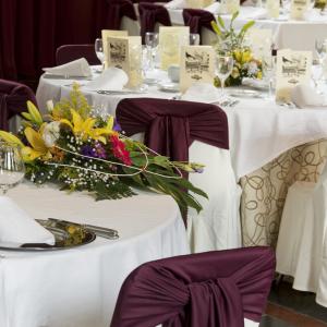 Sillas blancas con lazos morados y centros de flores decoran las mesas del salón de banquetes del Parador de Arties