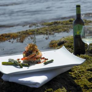 Timbal de langostinos y verduras de temporada a orillas del mar, con una copa de vino blanco