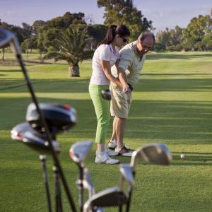 Una instructora mejora el golpe de un alumno en el campo de golf del Parador de Málaga Gibralfaro