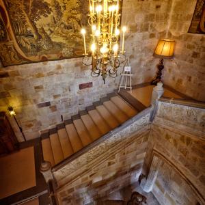Las escaleras de acceso a las habitaciones iluminadas por una gran lámpara colgante en el Parador de Zamora