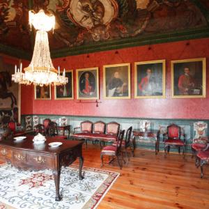 Una lámpara colgante ilumina un salón en el Parador Casa da Ínsua, decorado con retratos de época
