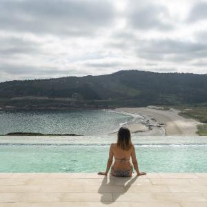 Una mujer disfruta de las vistas de la piscina exterior acristalada del Parador Costa da Morte