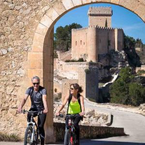 Una pareja pasea en bicicleta por la muralla medieval a la que está unida el Parador de Alarcón