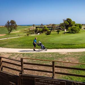 Un golfista pasea sus palos en el campo de golf del Parador de El Saler