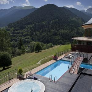 Jacuzzi exterior, piscina, terraza y solarium en el SPA &amp; Wellness del Parador de Vielha, con las montañas al fondo