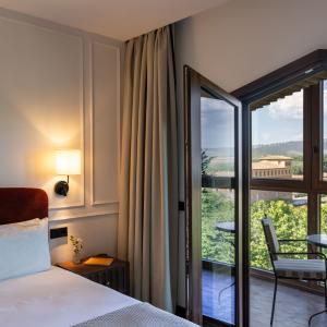 Detalle de cama, escritorio y televisor en habitación estándar del Parador de Olite-Erriberri