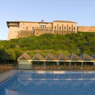 Vista de la piscina exterior del Parador de Carmona con el edificio del Parador al fondo.