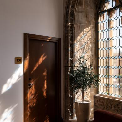 Imagen que muestra la puerta de una habitación junto a un ventanal de vidriera coloreada